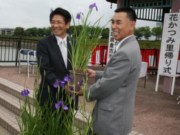 倉吉市の福井教育長に花かつみの鉢を手渡す町長