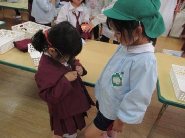 自分で着替えをしようとする姿を見守っているお姉さん