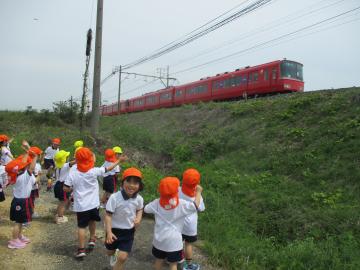 お散歩で、園児が電車を見て手を振っている